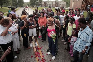 Mourning mother: Lesley McSpadden, center, drops rose petals on the blood stains from her 18-year-old son Michael Brown who was shot and killed by police in the middle of the street in Ferguson.